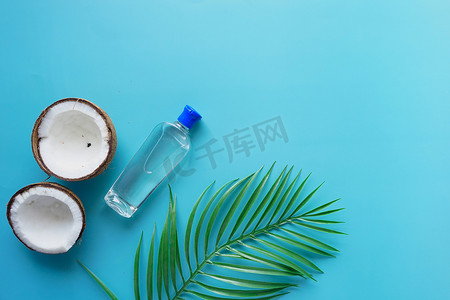 蓝色背景中新鲜椰子片和油瓶的顶部视图