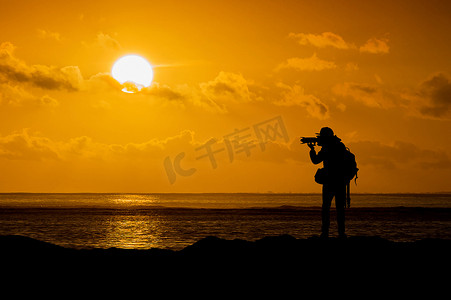 摄影师在日落时用相机剪影。