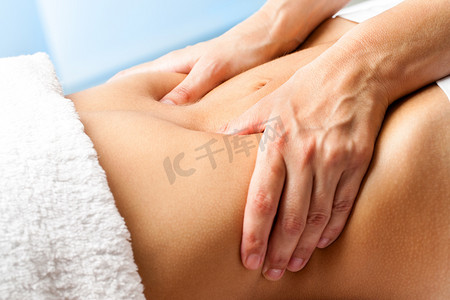 女性洗浴高兴摄影照片_宏观特写手按摩女性腹部。