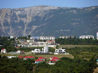 度假小镇的房屋屋顶位于绿色的山坡上，背后是雄伟的山脉。