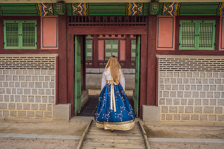 韩服图腾摄影照片_在韩国宫殿穿着韩服的年轻白人女游客。