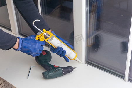 家杂摄影照片_工人正在使用聚氨酯泡沫填充窗扇和窗框之间的缝隙。