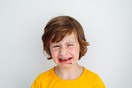 哭泣的孩子摄影照片_学校男孩孩子因脸上瘀伤疼痛而哭泣的画像。