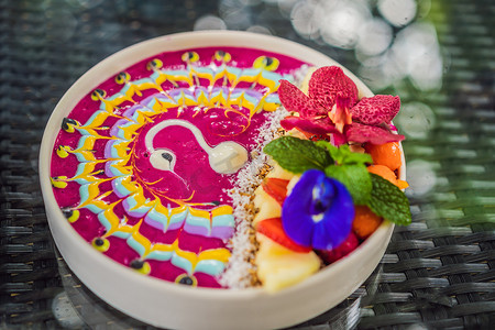 健康的热带早餐，带热带水果的冰沙碗，装饰着彩色酸奶、姜黄和螺旋藻的图案。