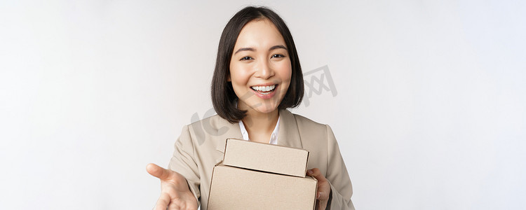女商人的画像，亚洲女售货员指着你，给盒子里的订单，穿着西装站在白色背景中