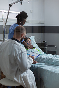护士记录摄影照片_医生在早上查房时检查剪贴板上的患者记录，而护士则戴上氧气面罩