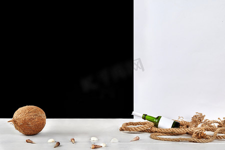 成熟的椰子、贝壳、带复制空间的玻璃瓶和里面的卷纸、黑白背景下表面的粗绳
