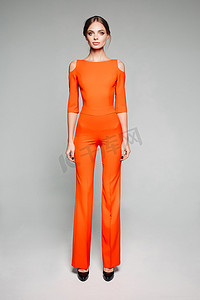 穿着休闲橙色连身裤和高跟鞋的高个子模特。