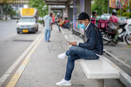 亚洲年轻人在城市使用智能手机，戴着脸 m