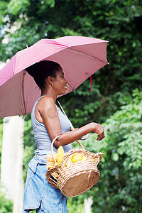 撑着雨伞，拿着篮子的年轻女子。