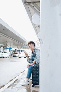 坐飞机摄影照片_年轻的亚洲乘客在机场等出租车