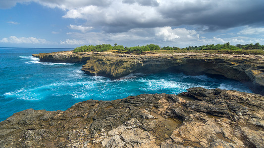 在巴厘岛附近蓝梦岛附近的岩石上冲浪
