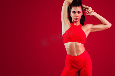 一位强壮的运动女舞者，穿着运动服、健身和运动动机，穿着红色背景，有复制空间。