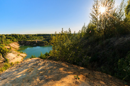 蓝天绿水摄影照片_有沙滩、绿水、树木和蓝天的山丘的采石场或湖泊或池塘