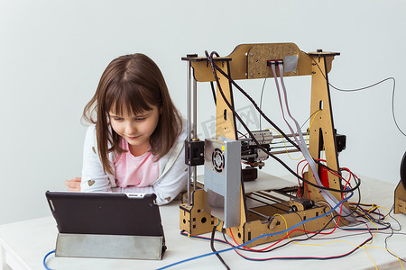 戴着 3d 打印百叶窗的可爱女孩正在看着她的 3d 打印机打印她的 3d 模型。
