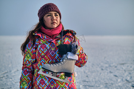 在结冰的湖面上滑雪后，一名妇女将冰鞋扛在肩上