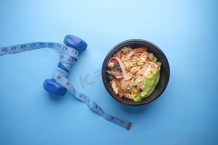 蓝色哑铃、新鲜蔬菜和测量带的健身概念