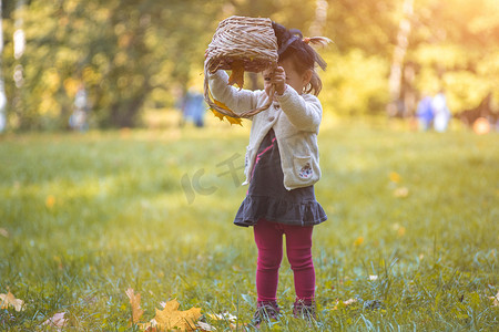小可爱女巫翻着篮子，在公园里倒秋叶。