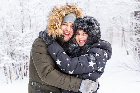 白雪皑皑的森林摄影照片_恋爱中的年轻情侣在白雪皑皑的森林里玩得开心。