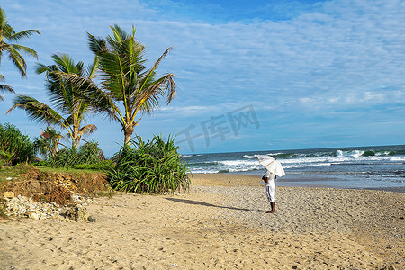 太阳伞摄影照片_太阳伞下站在沙滩上的人