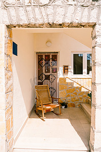 椅子阴影摄影照片_房子入口处的木制摇椅