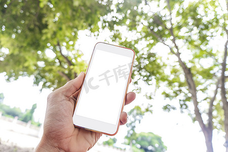 白屏模拟电话，亚洲男子手持智能手机，带有空白复制空间屏幕，用于您的短信或绿树散景背景清新风格的信息内容