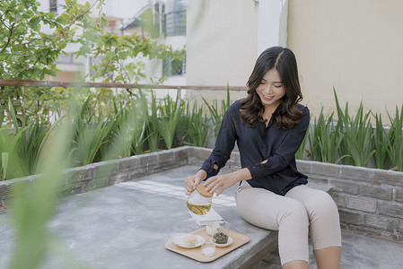 享受她舒适的大阳台的年轻亚裔妇女