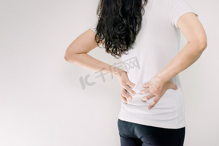 女性腰痛摄影照片_手扶着腰背后腰痛