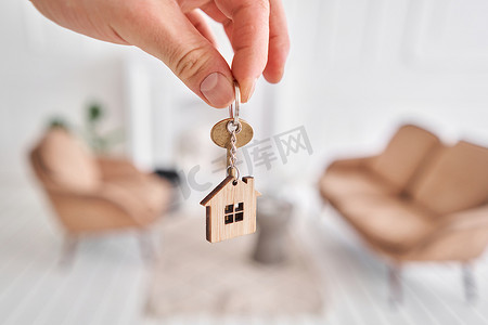 男人手拿着钥匙和房子形状的钥匙扣。