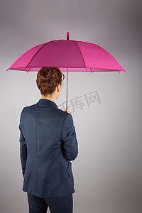 穿着西装打着粉色雨伞的女商人