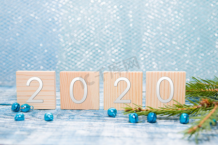 文字用木方块，2020 年新年，云杉树枝，闪亮的珠子，蓝色木质背景