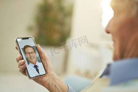 医生在线摄影照片_看着智能手机并与医生在线聊天的白人老人