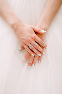 新娘优雅的手折叠在蓬松的婚纱裙子上，特写