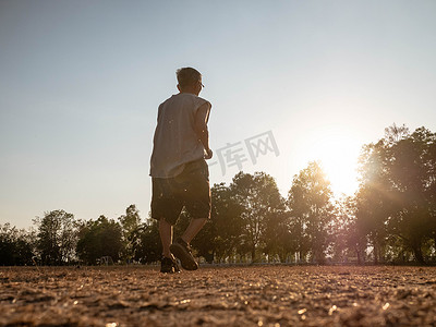 亚洲老人在日落天空背景下的公园里慢跑。