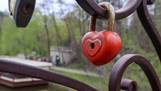 红色挂锁金属爱心形锁在桥上。