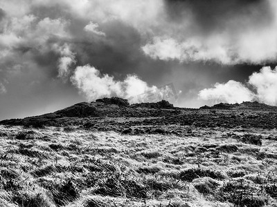 云层翻滚摄影照片_达特穆尔荒野山上崎岖的岩石露头，云层翻滚
