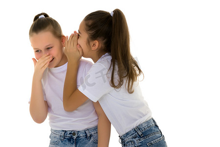 诉说摄影照片_两个性格开朗的小女孩在彼此的耳边分享秘密。
