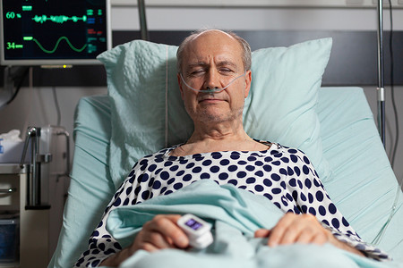 血氧计摄影照片_在医院病床上休息的老年男性病人的画像