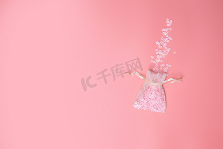 透明纱布摄影照片_粉红色背景质地的欧根纱袋，开出美丽的花朵，白色雏菊，春天，母亲节，爱情，假日最小概念。