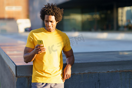 黑人脏辫摄影照片_黑人在锻炼休息时查看他的智能手机。