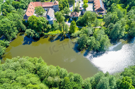 从空中看有护城河的 Neuhaus 城堡的池塘，有灌木和树木，在村庄的边缘
