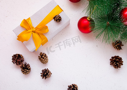 白色背景上带金色蝴蝶结、松枝和锥体的礼盒