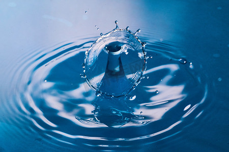 蓝元素摄影照片_碰撞在干净的蓝色表面上的两滴水