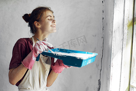 室内装修中摄影照片_手拿刷子在家庭室内装修中油漆的女人