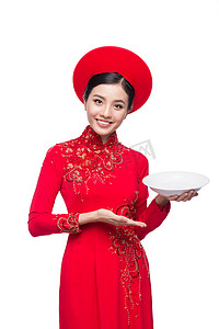 介绍产品摄影照片_穿着传统 Ao Dai 的越南女人微笑，并在白色背景下介绍产品。