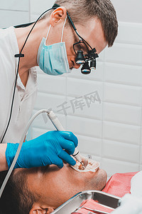 牙科诊所，私人诊所，牙医使用双筒望远镜以获得最佳效果和工作，去除牙垢的过程。