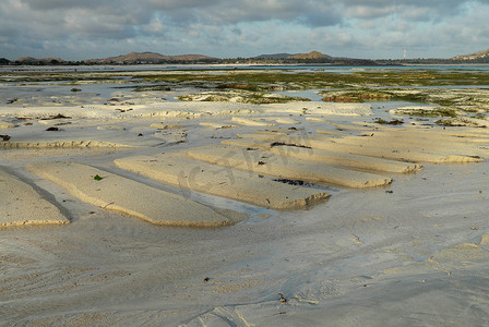 安静祥和摄影照片_日出时沙丘的前景焦点，在安静祥和的海滩上，海面上有光反射。