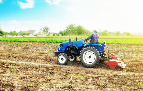 农业机械化摄影照片_农民在拖拉机上用铣床松动、研磨和混合土壤。