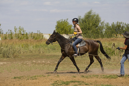 女子骑马摄影照片_骑马课程-骑马的年轻女子