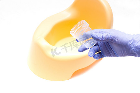 带蓝色一次性医用手套的女手在黄色罐子的背景上排出一罐尿液，收集尿液用于临床分析、复制空间、浅色背景
